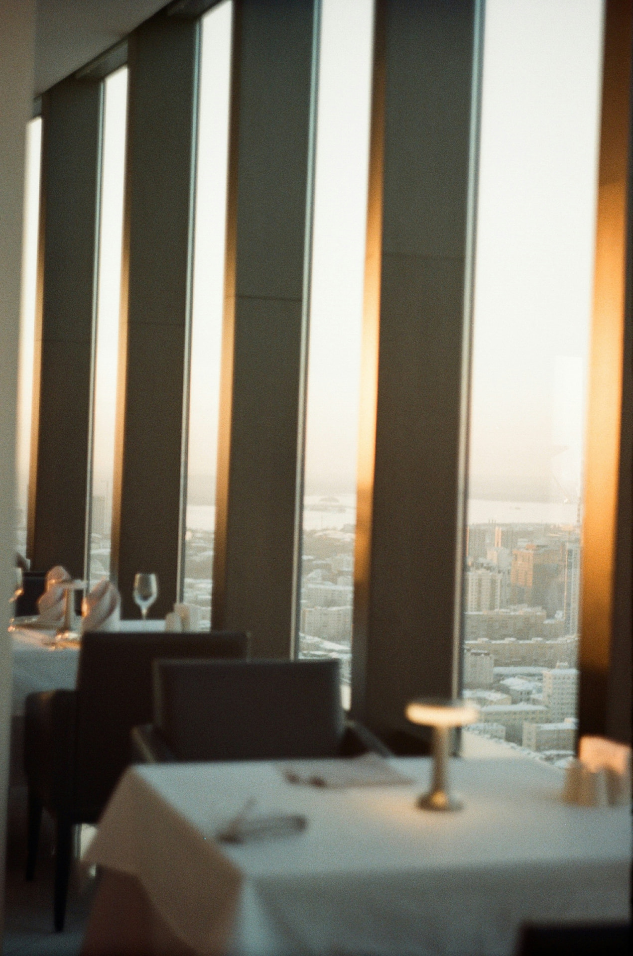 Elegant restaurant interior with tall windows and city views at sunset